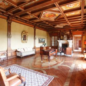 Salón social con chimenea, piano, artesonado y frescos del Parador Casa da Ínsua 